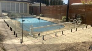 Frameless glass pool fencing with black composite spigots